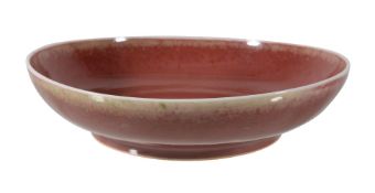 A Chinese copper-red dish, the rounded sides rising from a short tapered foot to a slightly flared