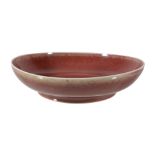 A Chinese copper-red dish, the rounded sides rising from a short tapered foot to a slightly flared