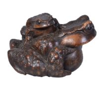 A Japanese Large Softwood Okimono carved as a toad sitting upon the back of a larger toad, the eye