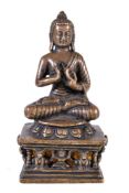 A Tibetan bronze figure of 'The Preaching Buddha', seated on a lion throne with diminutive figures