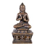 A Tibetan bronze figure of 'The Preaching Buddha', seated on a lion throne with diminutive figures