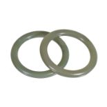 A pair of Chinese green jade bangles, of generally even tone with russet inclusions, 6.9cm