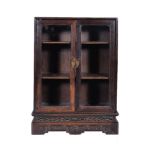 A small Chinese hardwood collector's cabinet, late Qing Dynasty, with two glazed doors, the base