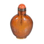A Chinese amber-coloured glass snuff bottle and stopper, engraved on one side with flowering peony