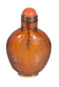 A Chinese amber-coloured glass snuff bottle and stopper, engraved on one side with flowering peony