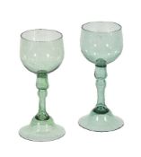 A pair of English pale-green wine glasses, circa 1750, the ovoid bowls supported on hollow