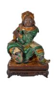 A Chinese glazed Pottery Figure of Guan Yu, seated on a hollowed base with his legs apart and one