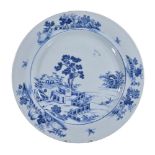 A Chinese blue and white dish, Qianlong, painted with building before a pine tree, 39cm diameter