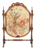 A Victorian walnut fire screen, circa 1860, the shield shaped screen with needlework banner