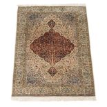 A woven carpet in Kashan style, the pale field decorated profusely with polychrome floral and