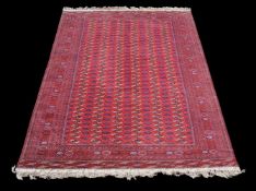 A Bokhara carpet, of overall design, the madder field decorated with guls and stylised foliate