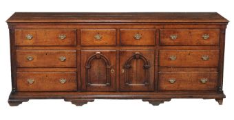 A George III oak dresser base, circa 1770, the plank top above the arrangement of drawers and