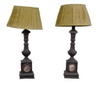 A pair of metal table lamps, with baluster stems above square section bases with porcelain plaques