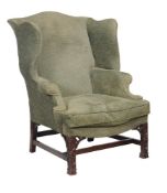 A mahogany and upholstered wing armchair, late 18th/early 19th century, the front legs carved with