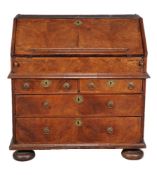 A Queen Anne walnut bureau, circa 1710, the hinged fall enclosing a concealed well and an