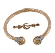 A gold coloured sprung bangle, the reeded arms to white paste accented ball terminals; together with