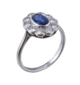 A 1950s sapphire and diamond cluster ring, the oval cut sapphire within a surround of brilliant