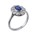 A 1950s sapphire and diamond cluster ring, the oval cut sapphire within a surround of brilliant