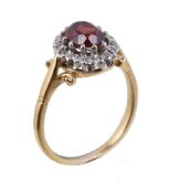 An 18 carat gold garnet and diamond ring, the central oval cut garnet within a surround of eight cut