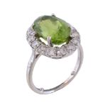 A peridot and diamond cluster ring, the oval cut peridot claw set within a surround of brilliant cut