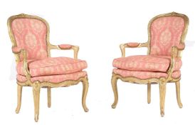 A pair of cream painted and parcel gilt armchairs, in Louis XV style, each moulded frame