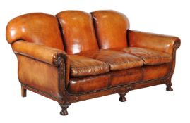 A carved mahogany and leather upholstered sofa, circa 1930, the triple padded back and triple