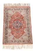 A Persian silk rug, the red field with central navy flowerhead medallion, the surround profusely