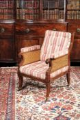 A Regency mahogany library bergere, circa 1810, the loose back and seat cushion with caned panels