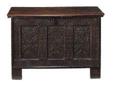 A panelled oak chest, mid-17th century, the hinged lid above a lunette carved frieze and triple