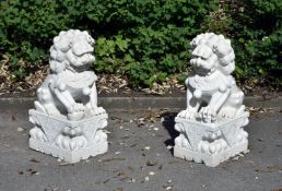 A pair of sculpted white marble models of Buddhistic lions, late 20th century, each seated on its