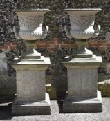 A pair of stone composition garden urns on plinths, second half 20th century, of Campana form with