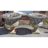 A pair of stone composition garden urns, 20th century, each with foliate cast everted rims above