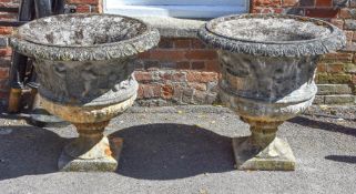 A pair of stone composition garden urns, 20th century, each with foliate cast everted rims above