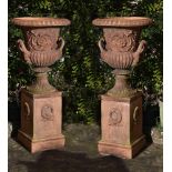 A pair of terracotta garden urns on plinths, second half 20th century, of Campana form, each with