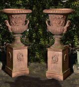 A pair of terracotta garden urns on plinths, second half 20th century, of Campana form, each with