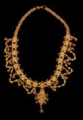 An Indian 1930s gold coloured wedding necklace, the graduated flower head panels suspending swags of