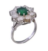 An emerald and diamond cluster ring, the oval mixed cut emerald with canted corners, within a