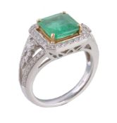 An emerald and diamond dress ring, the central step cut emerald in a four claw setting, within a