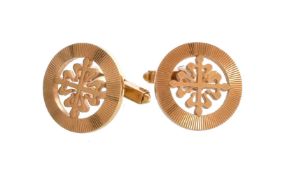 A pair of gold coloured cufflinks by Patek Phillippe, the circular panels pierced with the Patek