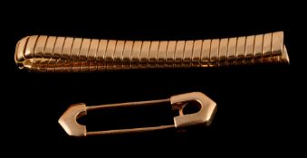 A novelty tie pin by Cartier, in the form of a gold coloured safety pin, signed Cartier with