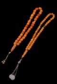 An amber and amber coloured bead prayer necklace, with an attached tassel, 31cm long; and a