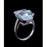 An aquamarine and diamond ring, the central rectangular cut aquamarine in a claw setting, between