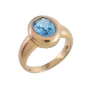 A blue topaz dress ring, the oval cut blue topaz within a polished gold coloured setting, the
