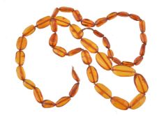 An amber bead necklace, the oval polished amber beads, measuring 11mm to 25mm long on a knotted