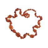A late 19th/early 20th century carved amber bead necklace, eleven of the beads are carved as