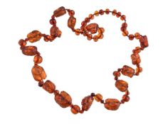 A late 19th/early 20th century carved amber bead necklace, eleven of the beads are carved as