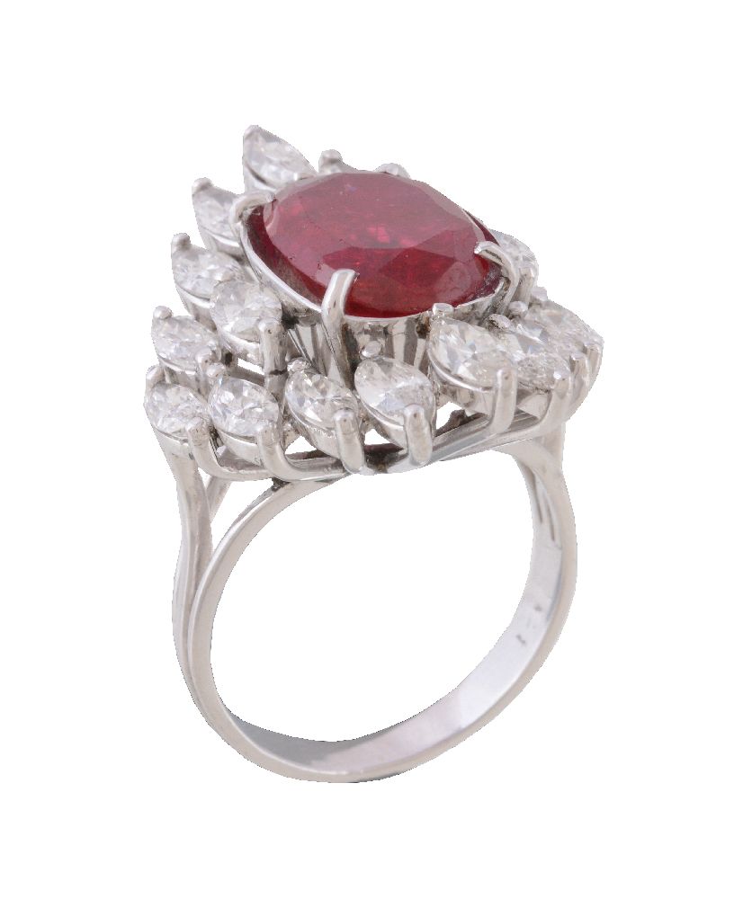 A ruby and diamond ring, the central oval cut ruby claw set within a surround of marquise cut