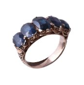 A sapphire ring, set with five graduating oval cut sapphires, in a carved scrolling setting,