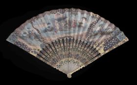 ϒ An ivory fan, 18th century, the guards and sticks pierced and painted, the paper leaf painted with