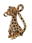 A 1960s enamel cheetah brooch, the textured seated cheetah with black enamel spots and green paste